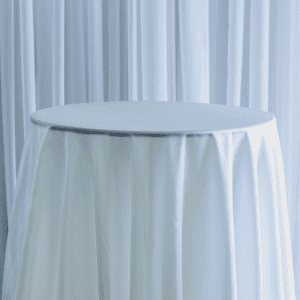 A basic cream polyester tablecloth on a round table used for wedding decor.