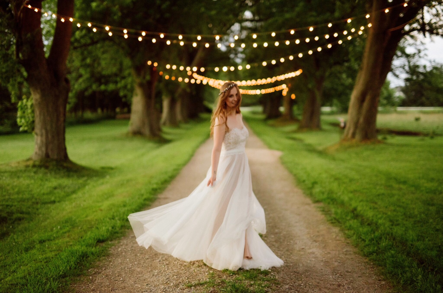 Wedding decor twinkle lights strung above the aisle with the bride below them.